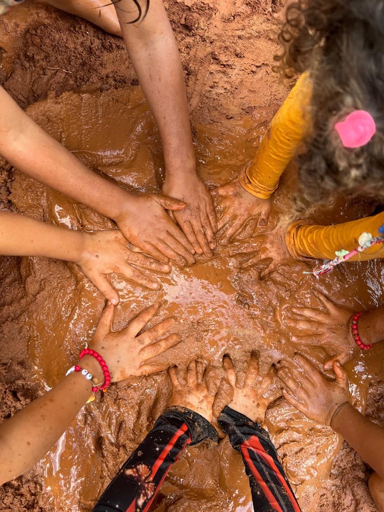 Mãos de crianças investigando barro